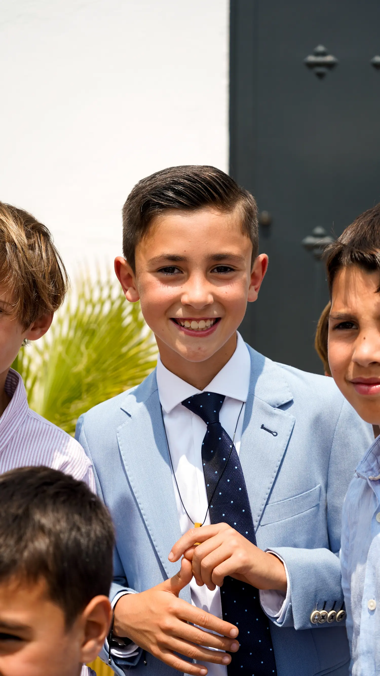 Retrato de niño sonriente vestido de comunión mirando a cámara