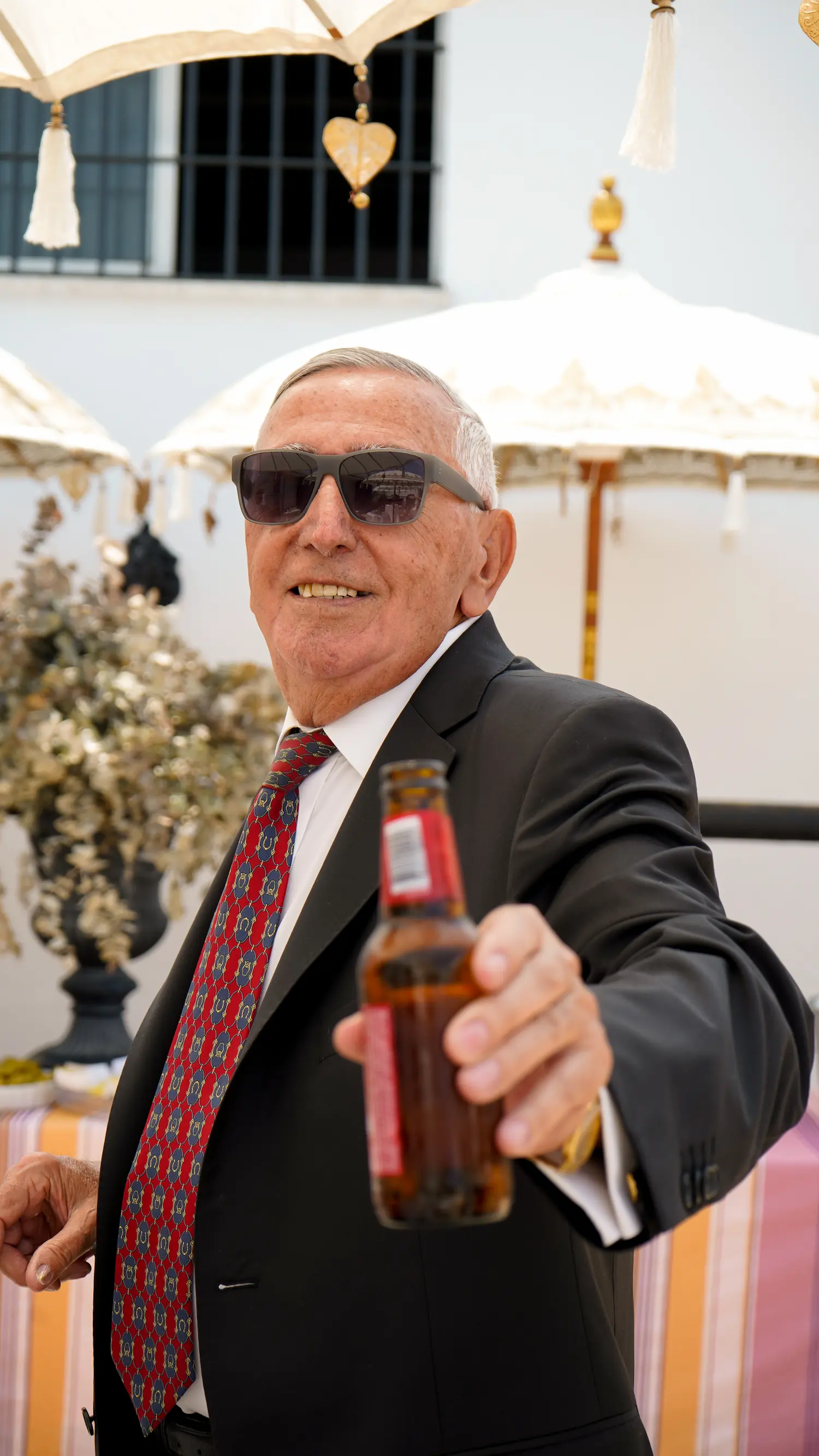 Invitado sonriente brindando con una cerveza durante el cóctel de una comunión
