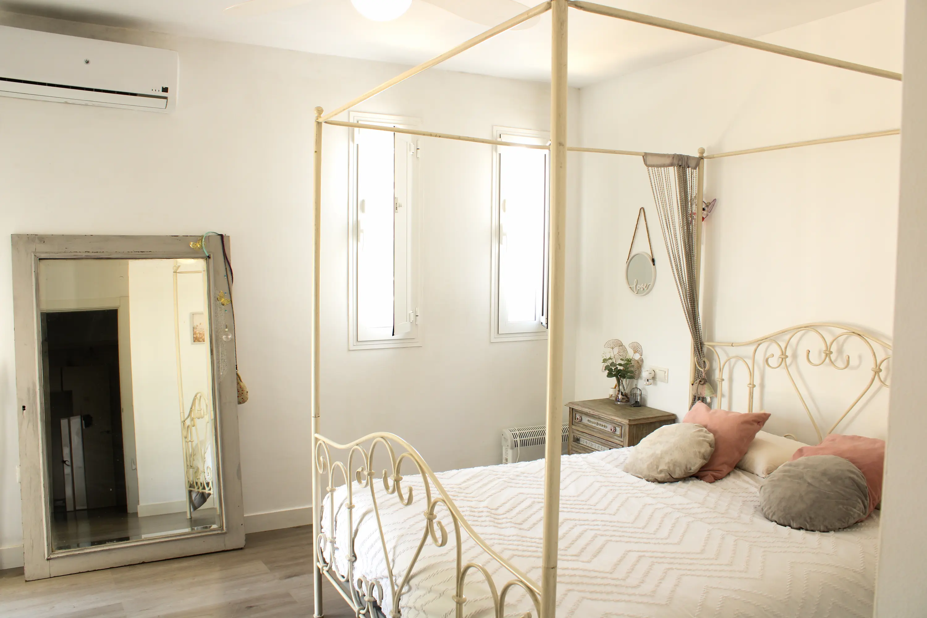 Master bedroom featuring a double bed with a mosquito net and a leaning floor mirror