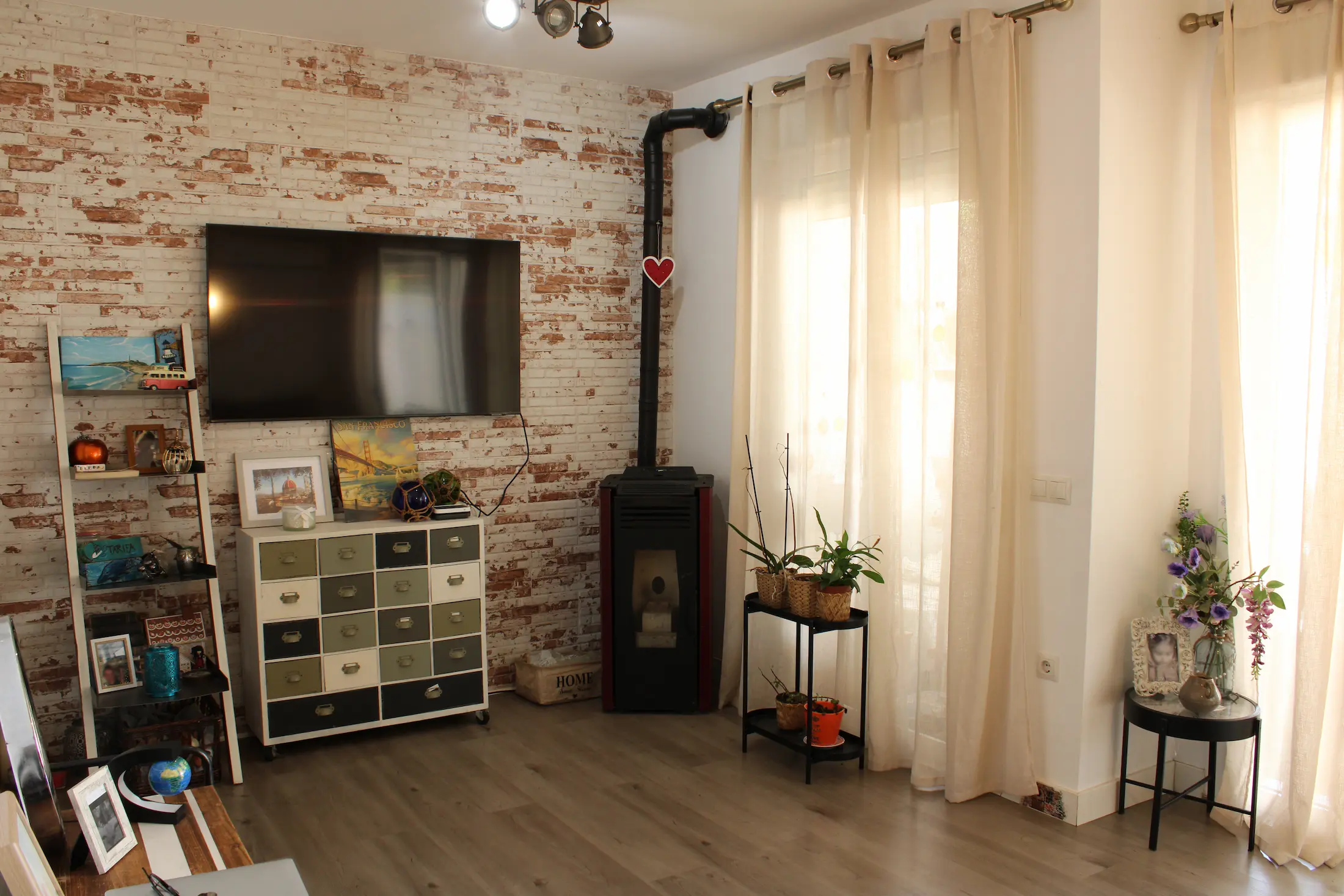 Living room with a wall-mounted TV, furniture, and a portable fireplace in the corner