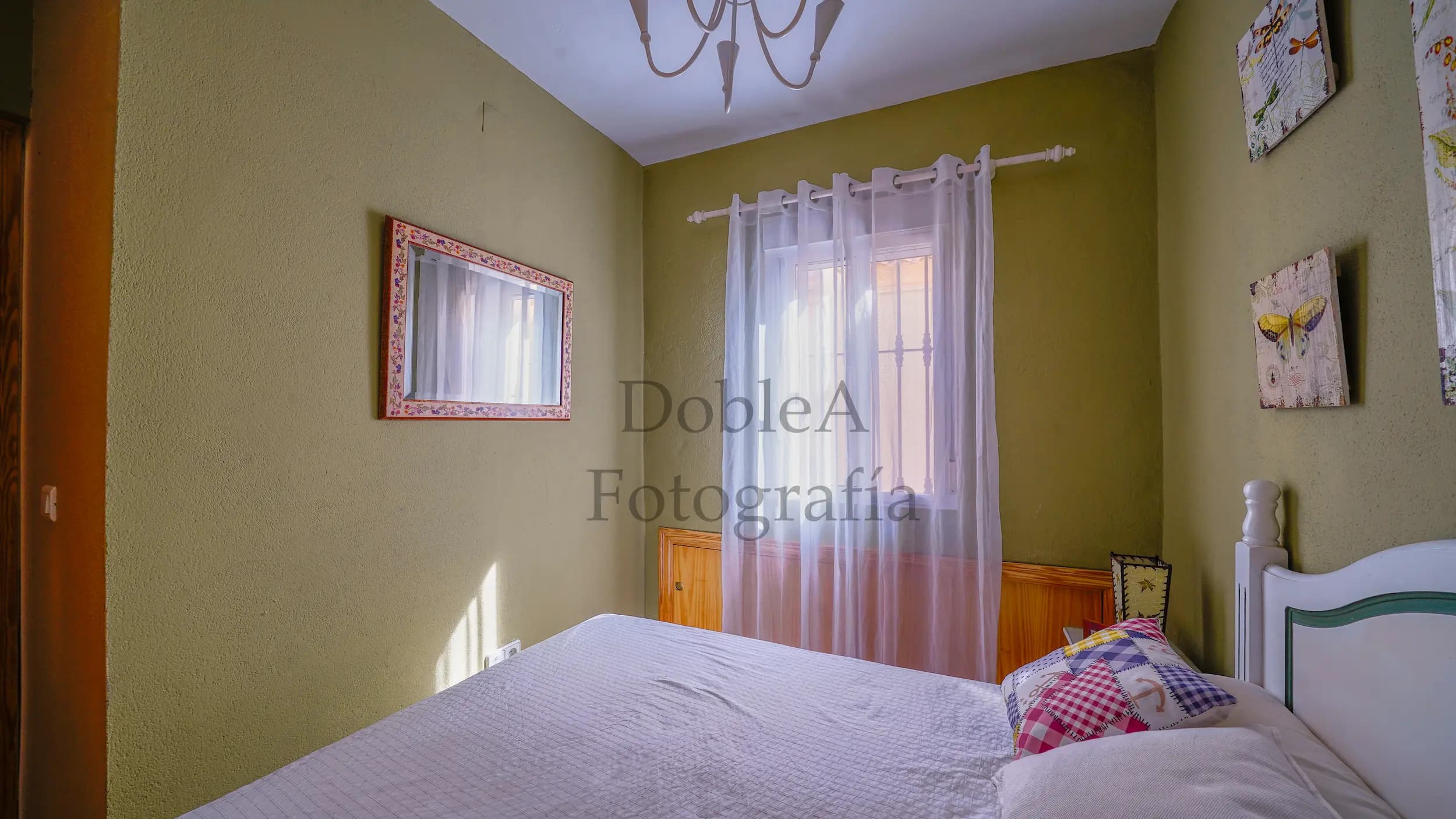 Bedroom with green walls, a double bed, and excellent natural light