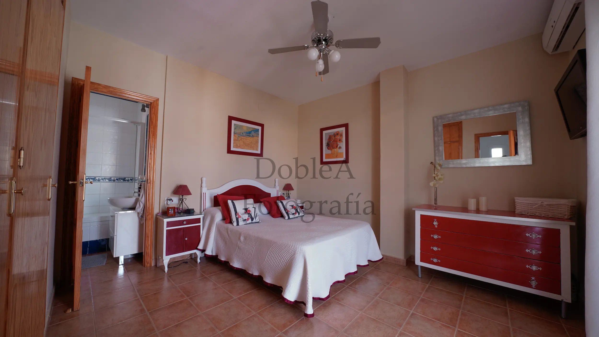 Spacious master bedroom with sand-colored walls, modern furniture, and direct access to the en-suite bathroom