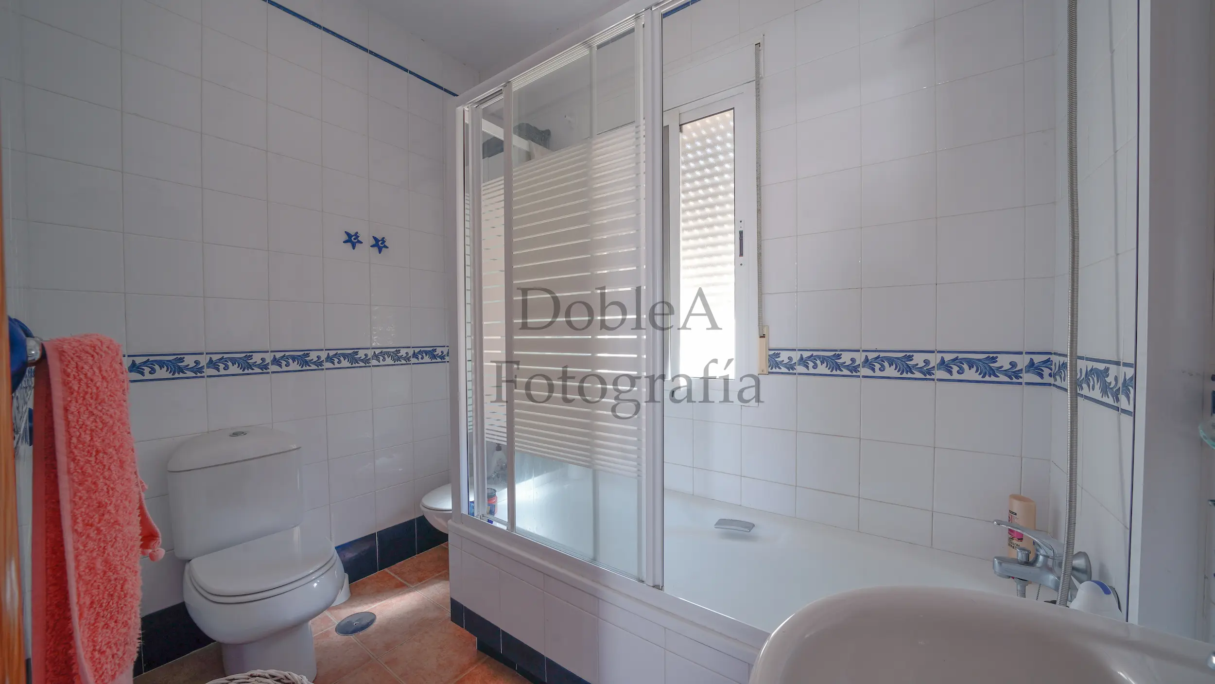 Real estate photograph of a full bathroom equipped with a bathtub with screen, toilet, and sink