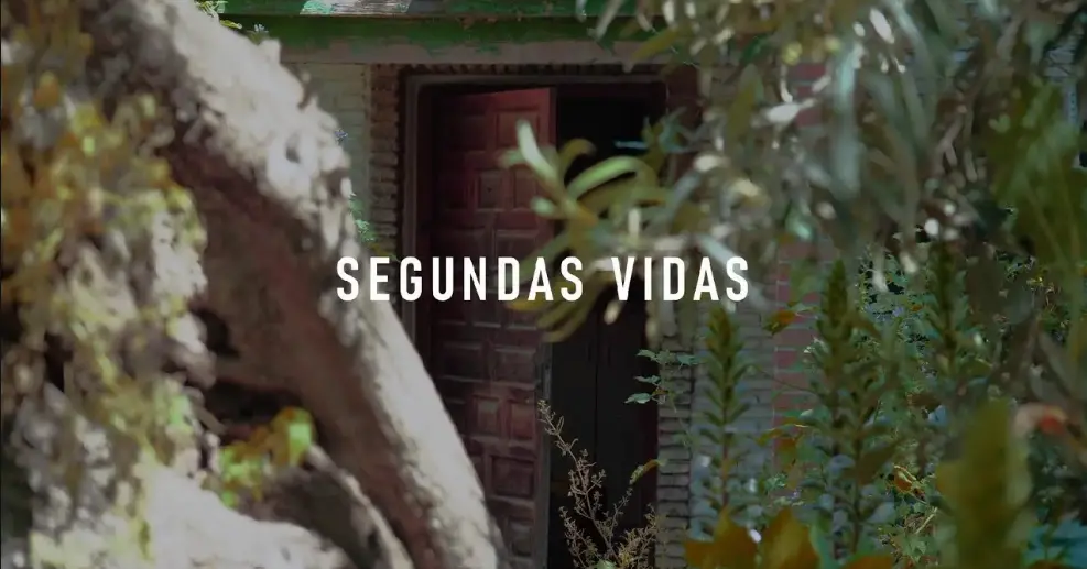 Fotograma de proyecto audiovisual destacando una puerta rústica enmarcada por vegetación natural con texto dinámico en el centro